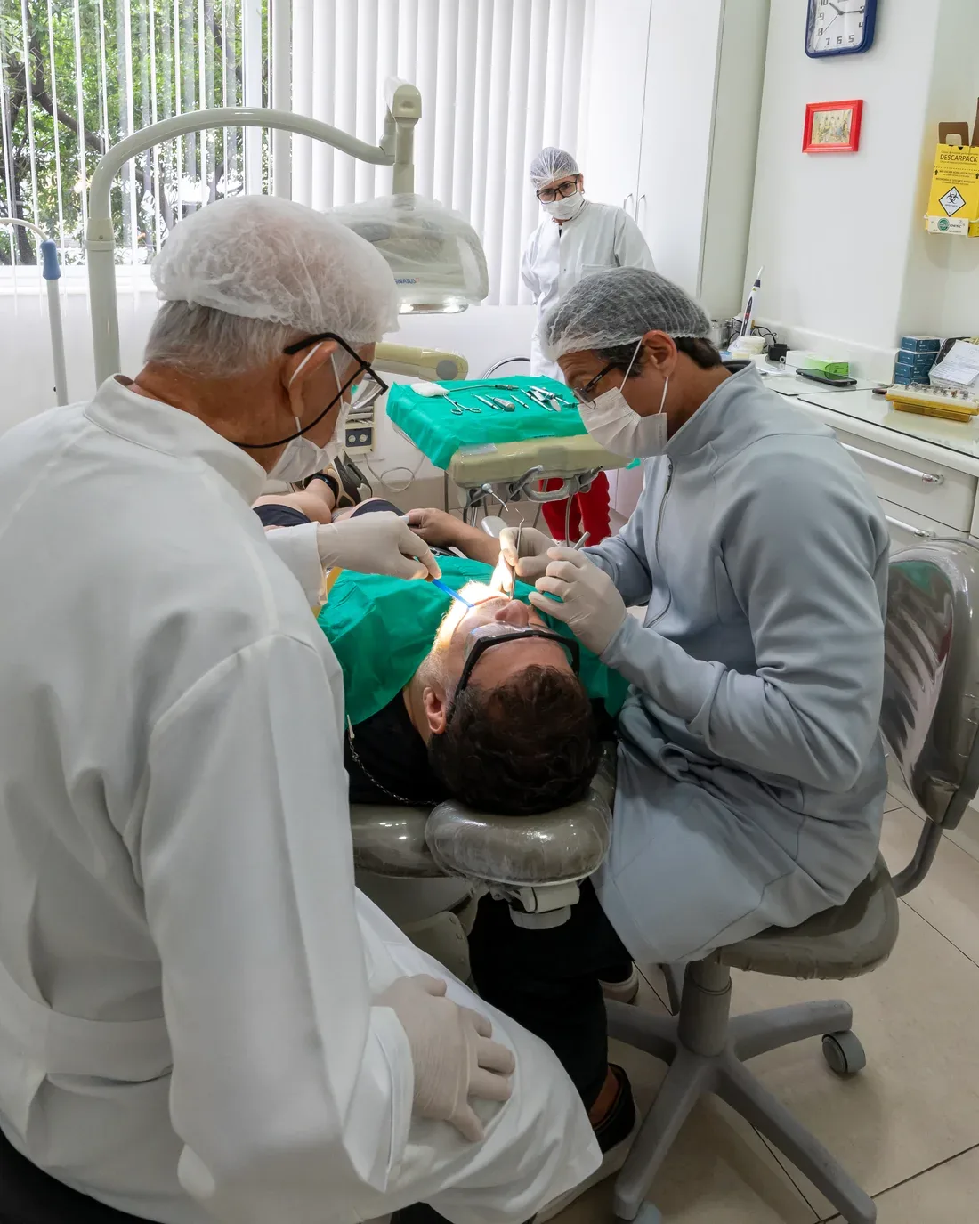 Sala de atendimento da clínica Martino Pacheco, com a equipe durante um procedimento odontológico, em Copacabana